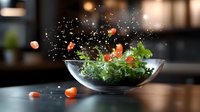 Fresh green salad with cherry tomatoes splashing in glass bowl against dark background, water drops flying in dynamic food composition.