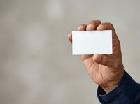 Man holding blank white business card or ticket in hand against neutral background, suitable for corporate branding and marketing materials.