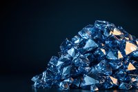 Sparkling blue crystal formation with geometric facets and golden light reflections on dark background, macro photography showing mineral structure details.