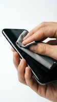 Person cleaning smartphone screen with microfiber cloth, isolated on white background for device care and maintenance concepts.