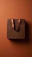Brown shopping bag with satin handles on warm terracotta background, casting shadow. Suitable for retail, e-commerce, packaging design, and luxury brand marketing materials.