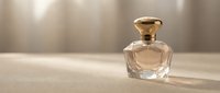 Elegant glass perfume bottle with golden cap on neutral beige surface, soft diffused lighting creating luxury cosmetics and fragrance product photography for beauty branding.