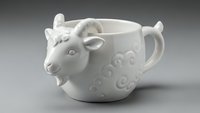 White ceramic sheep mug with decorative swirl patterns isolated on gray background for kitchen decor and drinkware design projects.
