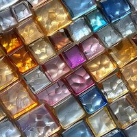 Colorful glass mosaic tiles in gold, blue, purple and silver with textured surface catching light and creating abstract geometric pattern. For luxury design backgrounds.