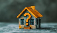 Miniature house model with large question mark symbol on facade against blurred background, representing real estate uncertainty and housing market decisions.