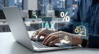 Professional accountant working on laptop with digital tax icons and financial symbols floating above keyboard in modern office environment.