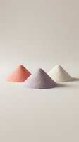Three colorful powder piles in coral pink, lavender purple and cream white arranged on neutral background for cosmetics and wellness branding.