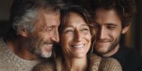 Happy multigenerational family portrait with smiling senior father, middle-aged mother and adult son embracing together in warm cozy sweaters at home.