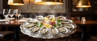 Fresh oysters on ice platter with lemon garnish served in upscale restaurant setting with warm ambient lighting and wine glasses for fine dining experience.