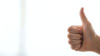 Hand showing thumbs up gesture against clean white background expressing approval and positive feedback for business success concepts.