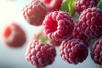 Fresh ripe raspberries macro shot showing detailed texture and natural frost coating on bright red berries against soft blurred background for food design.