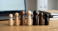 Wooden peg people figures in various skin tones representing diversity and inclusion in workplace teamwork and collaboration concepts.