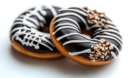 Chocolate glazed donuts with white stripes and sprinkles on white background. Close up view of sweet pastry dessert with dark and white chocolate decoration.