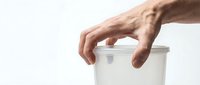 Male hand reaching for white cylindrical container on clean background. Modern minimalist product interaction concept for packaging design.