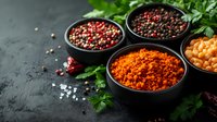 Aromatic spices and seasonings in black bowls on dark background with fresh herbs, peppercorns, chili powder and salt crystals for cooking and seasoning.