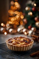 Homemade custard tart with caramelized top on cooling rack, cinnamon sticks nearby, festive Christmas tree lights bokeh in background.