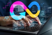 Business professional typing on laptop with colorful infinity loop symbol representing continuous improvement and digital transformation workflow.