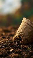 Burlap sack filled with rich organic soil on garden ground with natural bokeh background for sustainable farming and gardening projects.