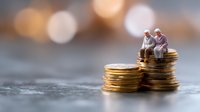 Senior couple sitting on stack of gold coins, retirement savings concept with warm bokeh background and copy space for financial planning message.