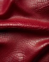 Luxurious red crocodile leather texture with deep embossed pattern and wavy surface creates elegant background for fashion and luxury goods design projects.