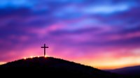 Silhouette of Christian cross on hilltop against dramatic purple and orange sunset sky with glowing clouds, spiritual and religious background concept.