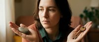 Young woman holding smooth stones in open palms during meditation practice. Mindful wellness concept for spa, healing therapy, balance and relaxation.