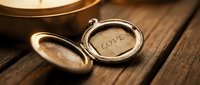 Open vintage gold locket with engraved word Love on rustic wooden surface, warm romantic atmosphere, antique jewelry keepsake.