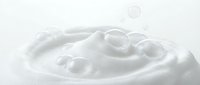 Creamy white cosmetic texture with smooth swirls and bubbles on clean background for skincare and beauty product applications.