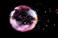 Translucent soap bubble with purple and pink iridescent surface floating against black background with scattered light particles and bokeh effects.