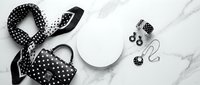 Monochrome flat lay composition featuring black and white polka dot accessories including scarf, handbag, and jewelry arranged on marble surface for fashion styling and design projects.