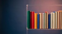 Colorful books arranged on wooden shelf against gradient background from dark blue to warm pink creating modern library atmosphere for education concepts.