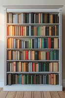 Classic white wooden bookshelf filled with vintage hardcover books in various colors and sizes arranged neatly on six shelves against light wall with wooden floor.