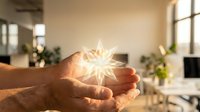 Hands holding glowing star-shaped light bulb in modern office workspace with plants and windows, symbolizing innovation, ideas, creativity and sustainable energy solutions.