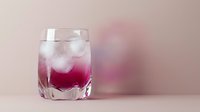 Refreshing pink gradient cocktail with ice cubes in clear glass on soft pastel background for beverage and drink concepts.
