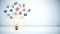 Glowing light bulb with business icons floating above representing innovation, creativity, and entrepreneurial ideas for startup success and growth.