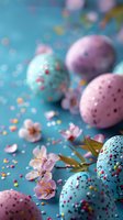 Decorated Easter eggs in pastel pink and blue with colorful sprinkles scattered on turquoise background, adorned with delicate cherry blossom flowers and golden leaves.