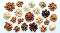 Assorted nuts and seeds including almonds, cashews, peanuts, and macadamia nuts arranged on white background for food, nutrition, and healthy eating content.