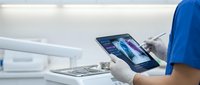 Medical professional using digital tablet for patient data analysis in modern healthcare facility with advanced diagnostic equipment.