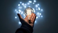 Hand holding glowing vintage light bulb with bokeh lights background representing innovation creativity and bright ideas for business solutions.
