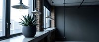 Modern industrial workspace with potted plant on windowsill, pendant lamp, and minimalist dark interior design for contemporary office or loft decor projects.