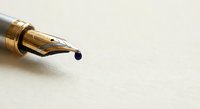 Elegant gold fountain pen nib with ink drop on textured paper surface for luxury writing and calligraphy projects.