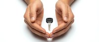 Hands forming protective circle around car key on white background symbolizing vehicle security and insurance protection concept for automotive safety.