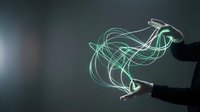 Hands creating magical green light trails in dark space with flowing energy streams and luminous effects for creative projects.