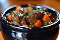 Hearty beef stew with tender meat chunks, bright orange carrots and fresh herbs in rich brown gravy served in dark ceramic bowl, comfort food photography.