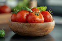 Fresh ripe red tomatoes with water drops and green leaves in wooden bowl on dark background, close up view for food photography and cooking blogs.