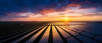 Solar panel farm at sunset with dramatic orange and golden sky, showcasing renewable energy technology and sustainable power generation for environmental and industrial applications.