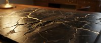 Black marble countertop with gold veining under warm lighting, showcasing luxury interior design and elegant surface material for kitchen or bathroom renovation projects.