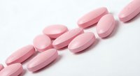 Pink oval tablets scattered on white background isolated for pharmaceutical and healthcare design projects.