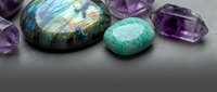 Polished gemstones collection featuring labradorite with iridescent flash, amazonite and amethyst crystals on gray surface for jewelry design.