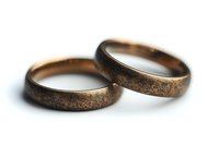 Pair of antique bronze wedding bands with rustic patina texture against white background, showing romantic commitment and traditional marriage symbolism.